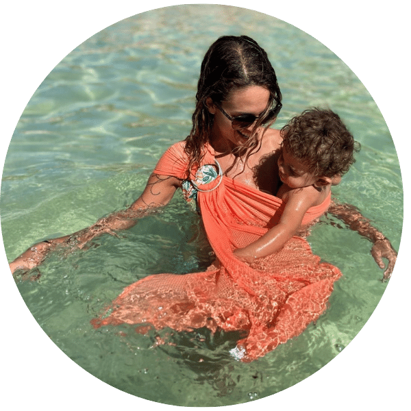 mama y bebe con bandolera portabebes de agua disfrutando de un ba&ntilde;o en la playa